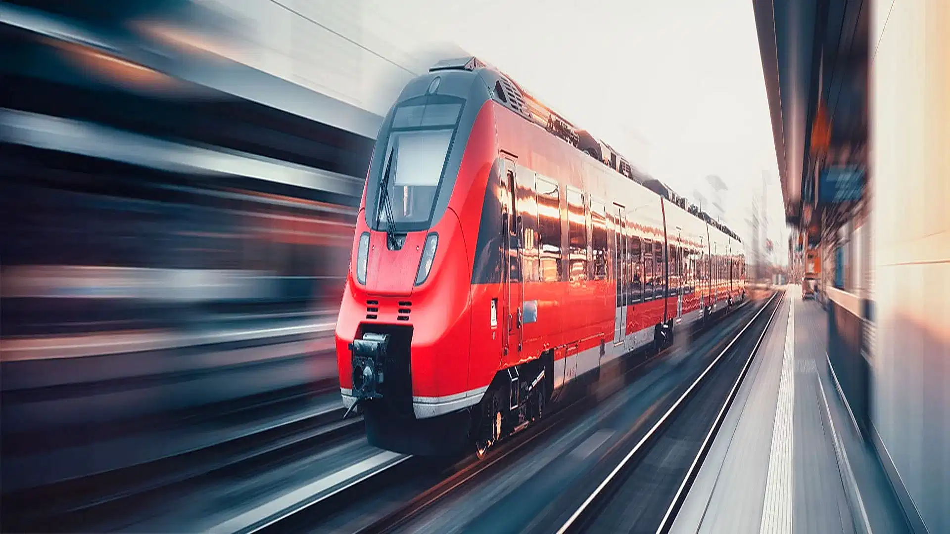 Ein roter Regionalzug fährt durch einen Bahnhof