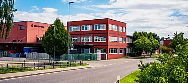 rotes Firmengebäude mit Produktionshalle umgeben von grüner Natur