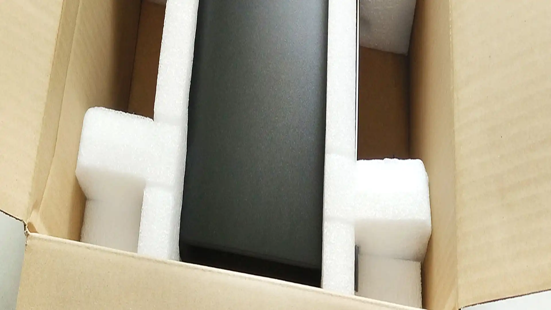 schwarzes Gerät von weißem Verpackungsschaum in einem Karton gesichert